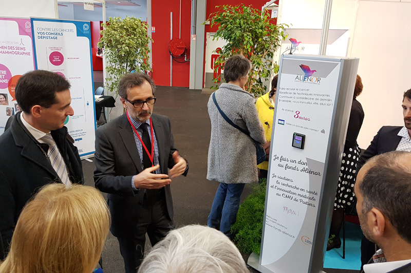 Stéphan Maret, directeur de la communication et du mécénat du CHU de Poitiers et trésorier du fonds Aliénor, présente aux officiels, lors de l’inauguration du salon, la borne de dons, aux côtés d’Amaury de Préville, directeur régional d’AG2R La Mondiale.